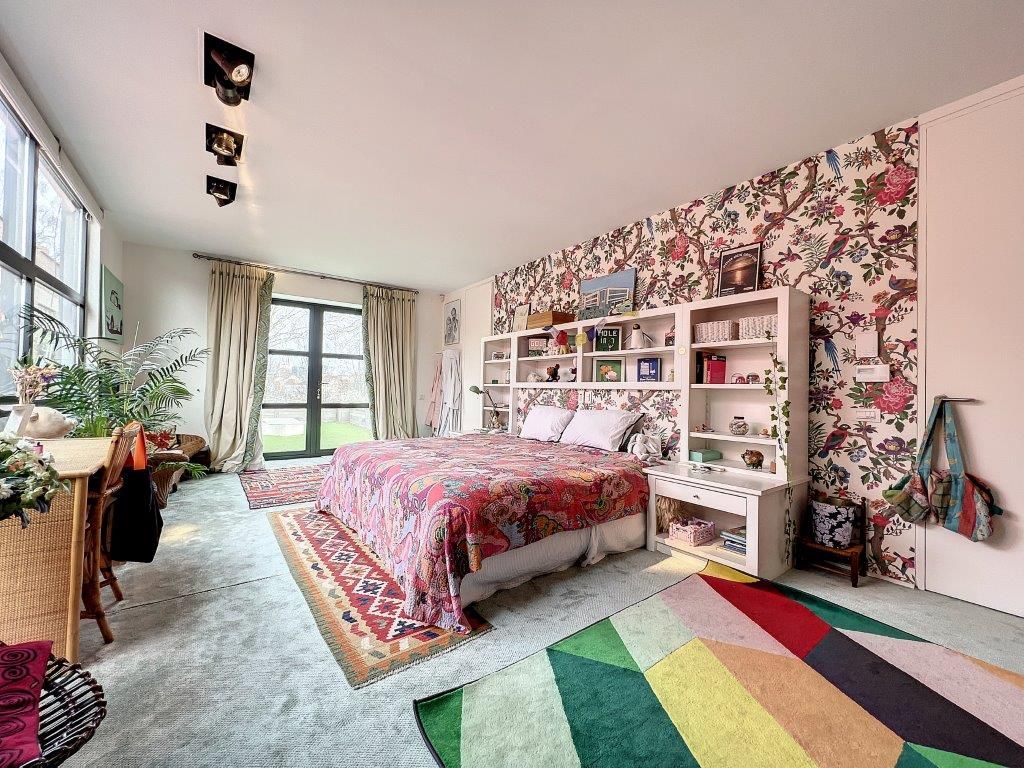 Chambre colorée et chaleureuse avec lit, bibliothèque, tapis géométriques et plantes naturelles.