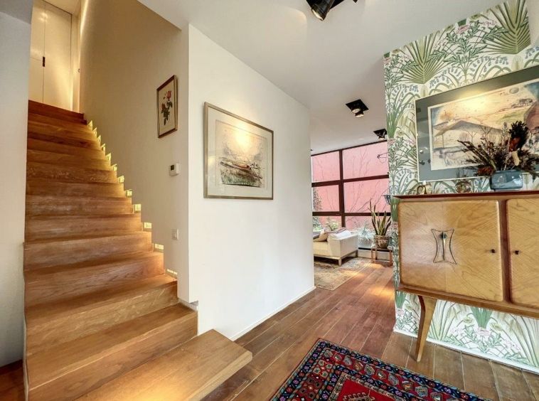 Entrée moderne avec escalier en bois, décoration naturelle et espace lumineux.