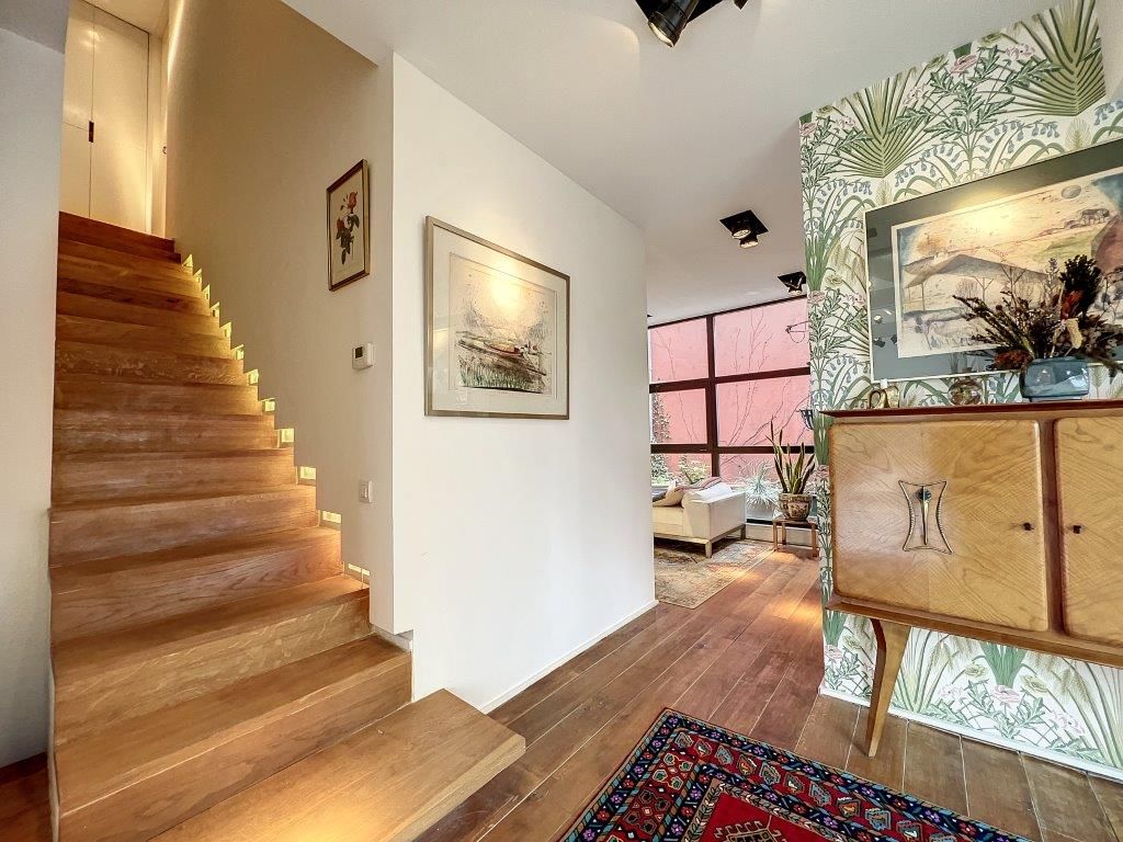 Entrée moderne avec escalier en bois, décoration naturelle et espace lumineux.