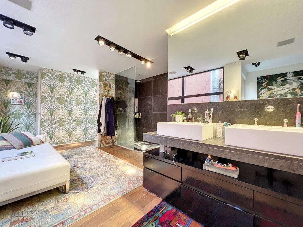 Salle de bain élégante avec douche en verre, double vasque, espace détente cosy et design moderne.