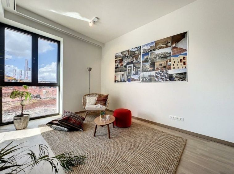 Salon moderne lumineux avec mobilier minimaliste, fenêtres, décor artistique, ambiance chaleureuse et naturelle.