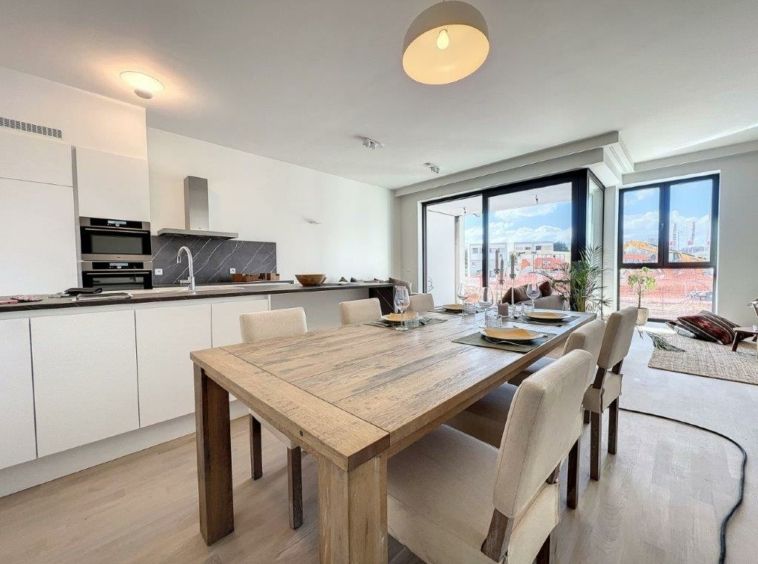 Salon contemporain lumineux avec grande table en bois et vue extérieure, parfait pour recevoir.