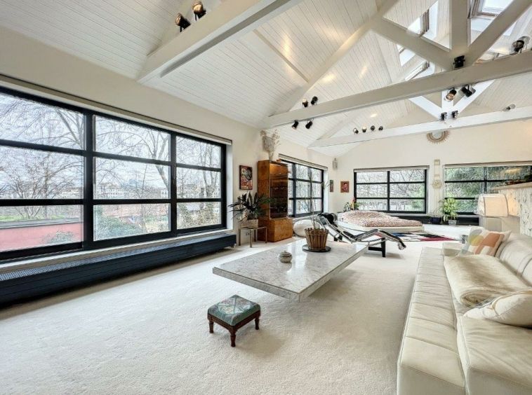 Salon moderne lumineux avec grands fenêtres, mobilier blanc, décor minimaliste et ambiance chaleureuse.