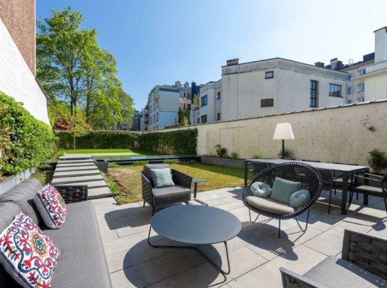 Espace extérieur moderne avec mobilier, jardin verdoyant et vue urbaine à Bruxelles.
