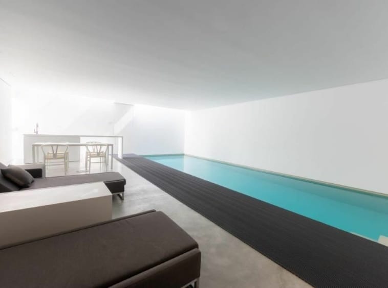 Piscine intérieure moderne avec espace détente, bar élégant et ambiance zen pour relaxation et sport.