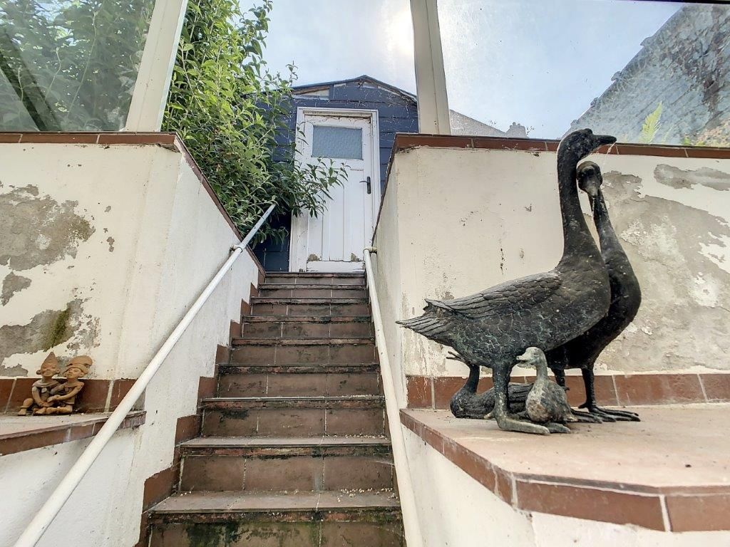 Escalier ancien avec sculpture de canards en métal dans un jardin bucolique et charmant.