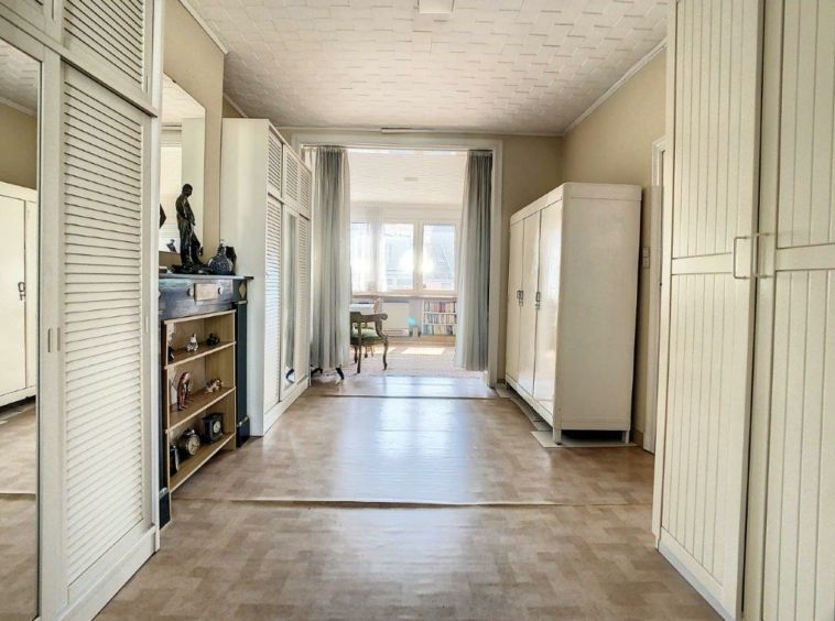 Couloir lumineux et minimaliste avec rangement, coin de repos et décoration élégante.
