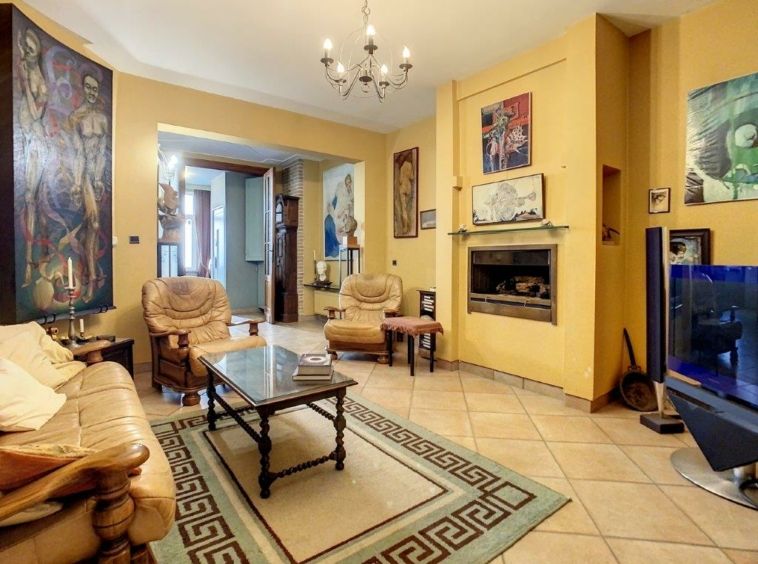 Salon chaleureux avec murs jaunes, œuvres modernes, cheminée, mobilier confortable et décoration colorée.