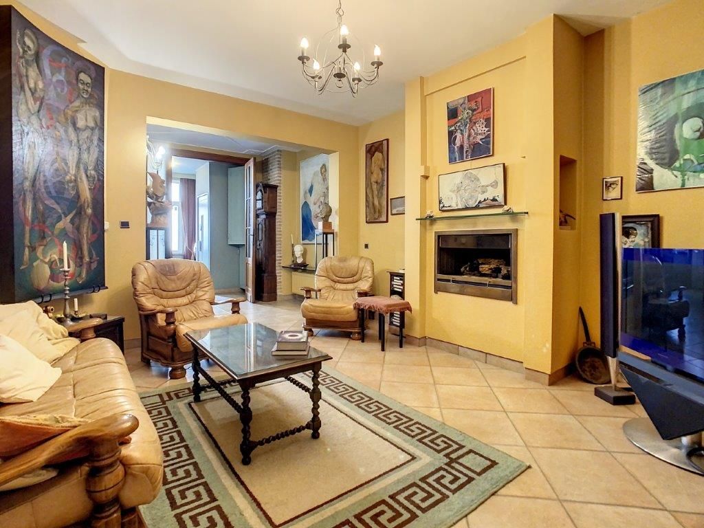 Salon chaleureux avec murs jaunes, œuvres modernes, cheminée, mobilier confortable et décoration colorée.