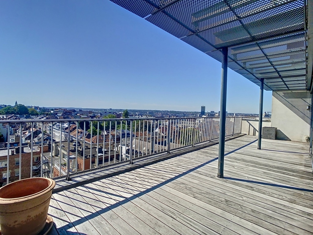Balcon en bois avec vue panoramique sur la ville ensoleillée, décor rustique et détente.