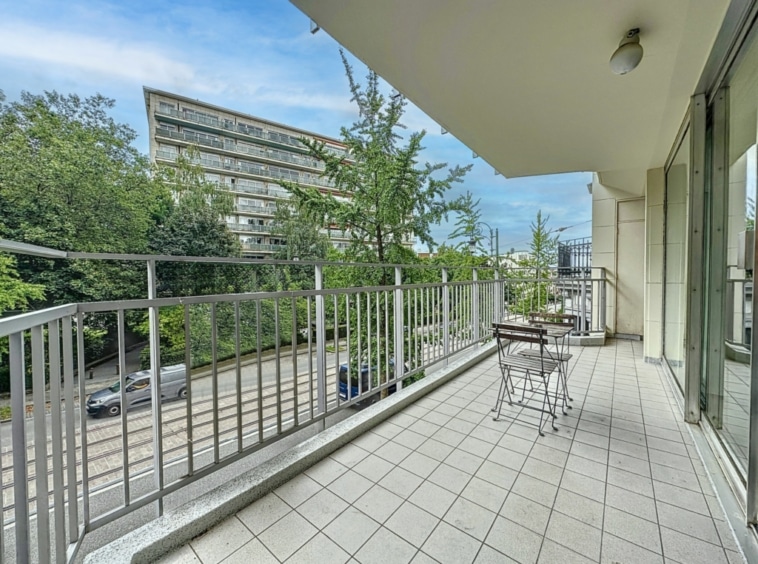 Balcon urbain spacieux avec vue sur la ville, mobilier minimaliste et ambiance paisible.