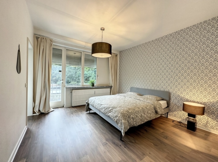 Chambre moderne et chaleureuse avec balcon, lumière naturelle et décoration minimaliste et cosy.
