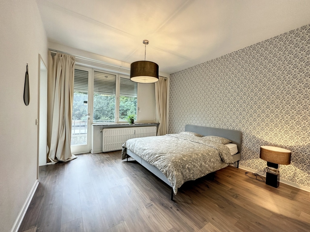 Chambre moderne et chaleureuse avec balcon, lumière naturelle et décoration minimaliste et cosy.