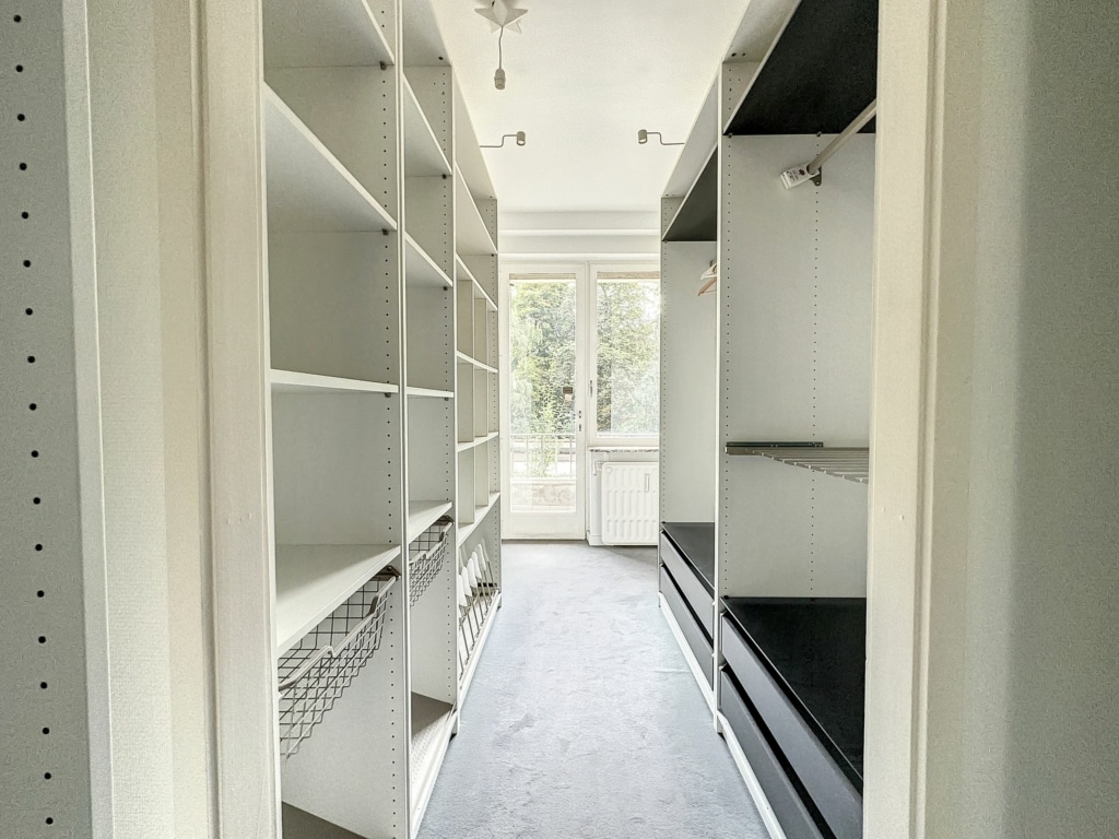 Dressing moderne lumineux avec étagères blanches, rangements pratiques et grande fenêtre naturelle.