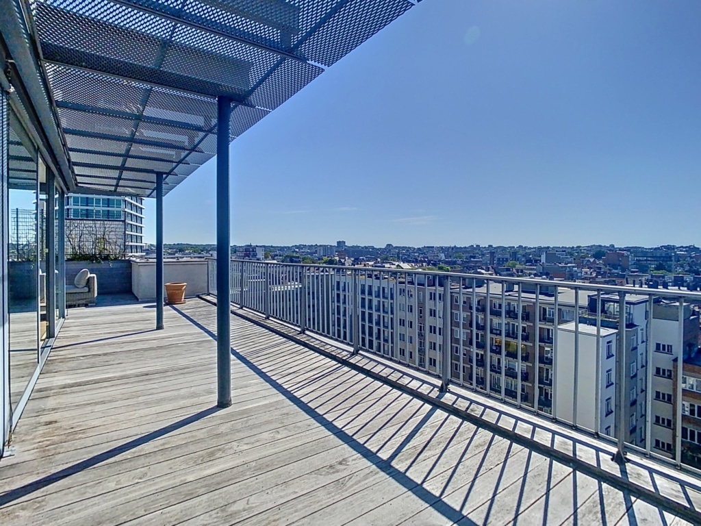 Terrasse urbaine moderne avec vue panoramique, mobilier élégant, plantes en pot et espace détente en plein soleil.