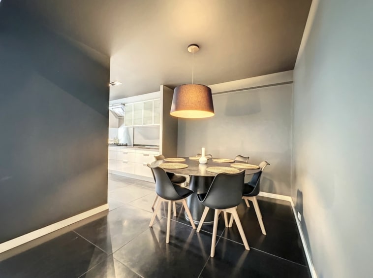 Salle à manger moderne avec table ronde, chaises ergonomiques, éclairage chaleureux, style épuré et élégant.