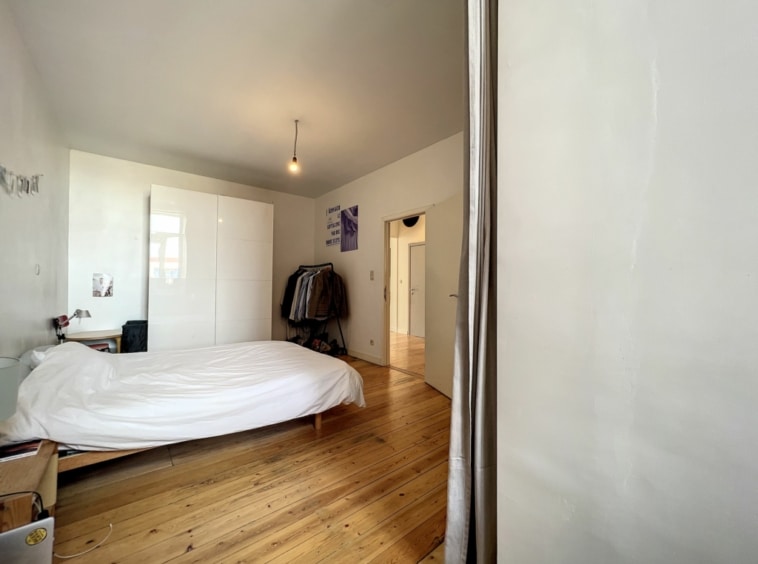 Chambre moderne et épurée avec grand placard, lit blanc et ambiance apaisante.