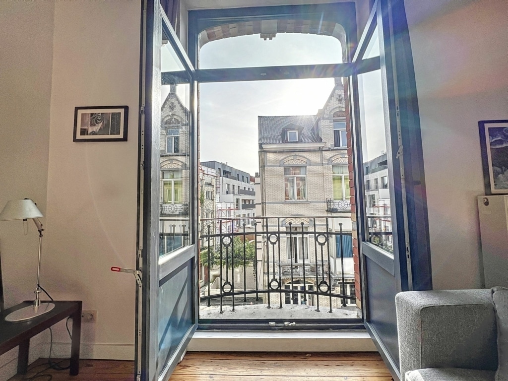 Intérieur lumineux avec vue urbaine, mobilier moderne, ambiance cosy et éclairage naturel.
