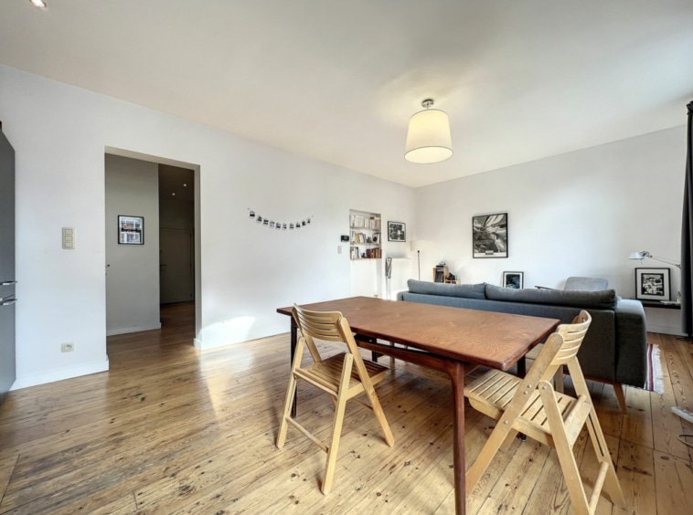 Salon moderne et convivial avec espace repas en bois, canapé gris et ambiance chaleureuse.