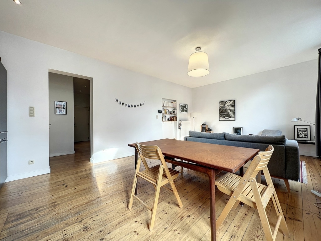 Salon moderne et convivial avec espace repas en bois, canapé gris et ambiance chaleureuse.
