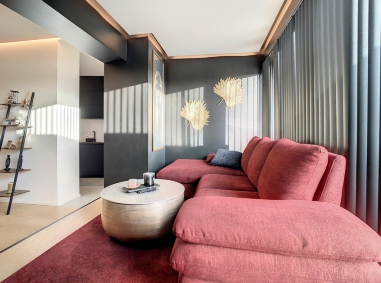 Salon contemporain chaleureux avec canapé rouge, décoration artisanale et lumière naturelle douce.