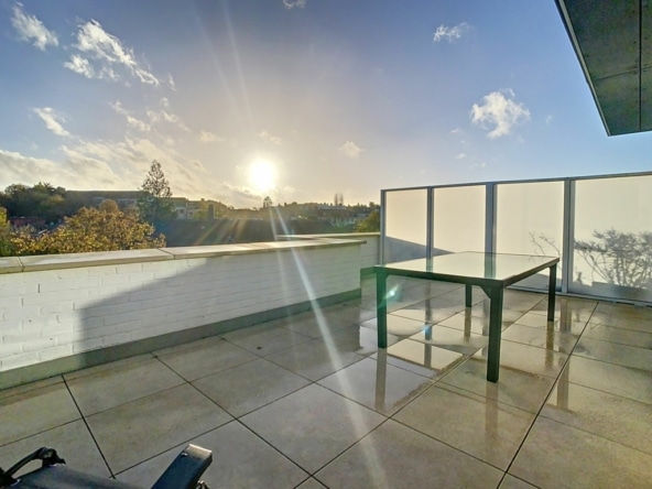 Terrasse au coucher du soleil avec vue panoramique, mobilier minimaliste et ambiance sereine.