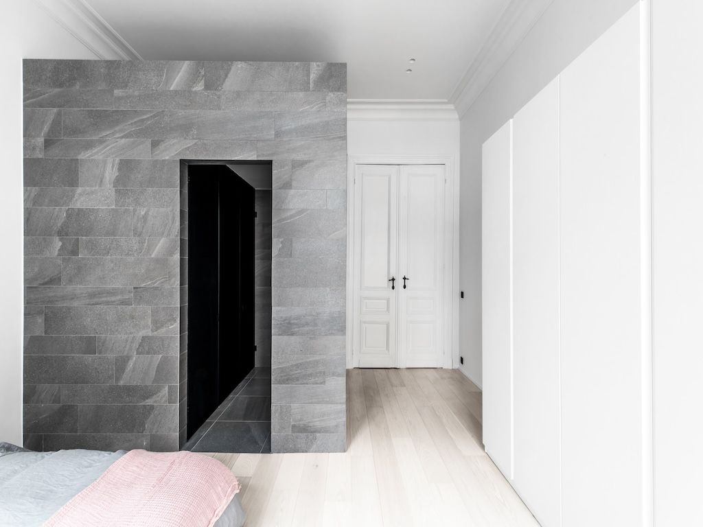 Chambre moderne minimaliste avec mur en pierre, portes doubles blanches et ambiance apaisante.