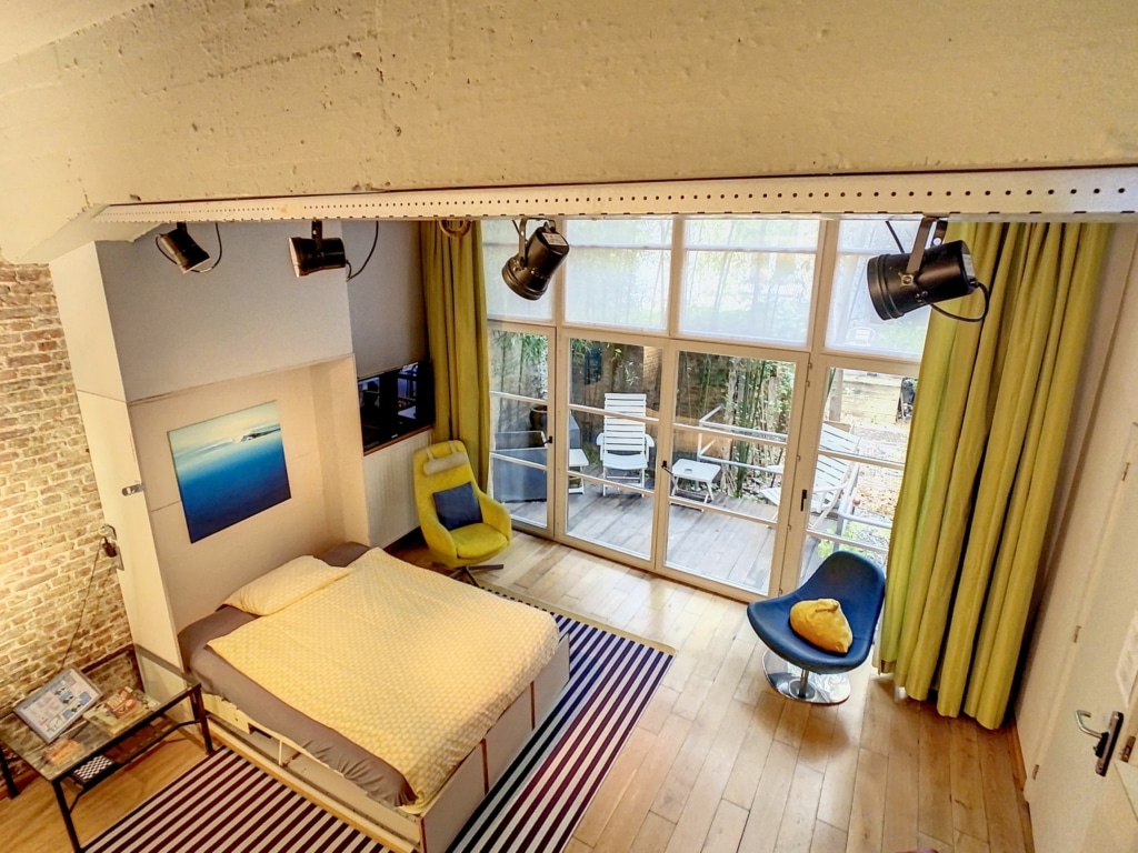 Chambre moderne lumineuse avec mur en brique, mobilier élégant et ambiance chaleureuse.