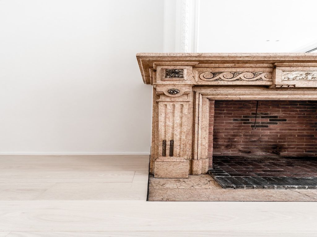 Cheminée élégante en marbre clair et briques rouges dans un intérieur moderne et lumineux.