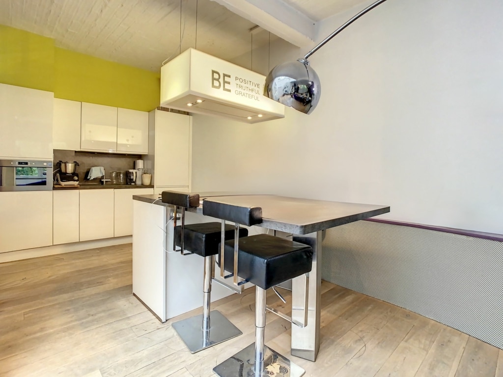 Cuisine moderne minimaliste avec bar, éclairage design BE et touches de vert vif.