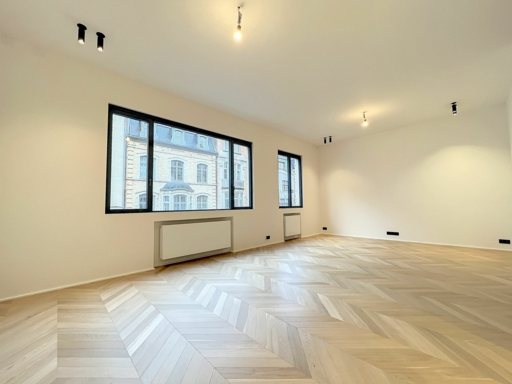 Intérieur moderne minimaliste avec parquet en chevron, lumière naturelle et ambiance chaleureuse.