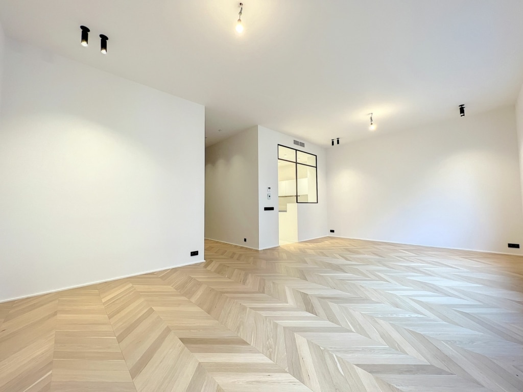 Espace intérieur moderne avec sol en parquet clair, murs blancs et lumière naturelle abondante.