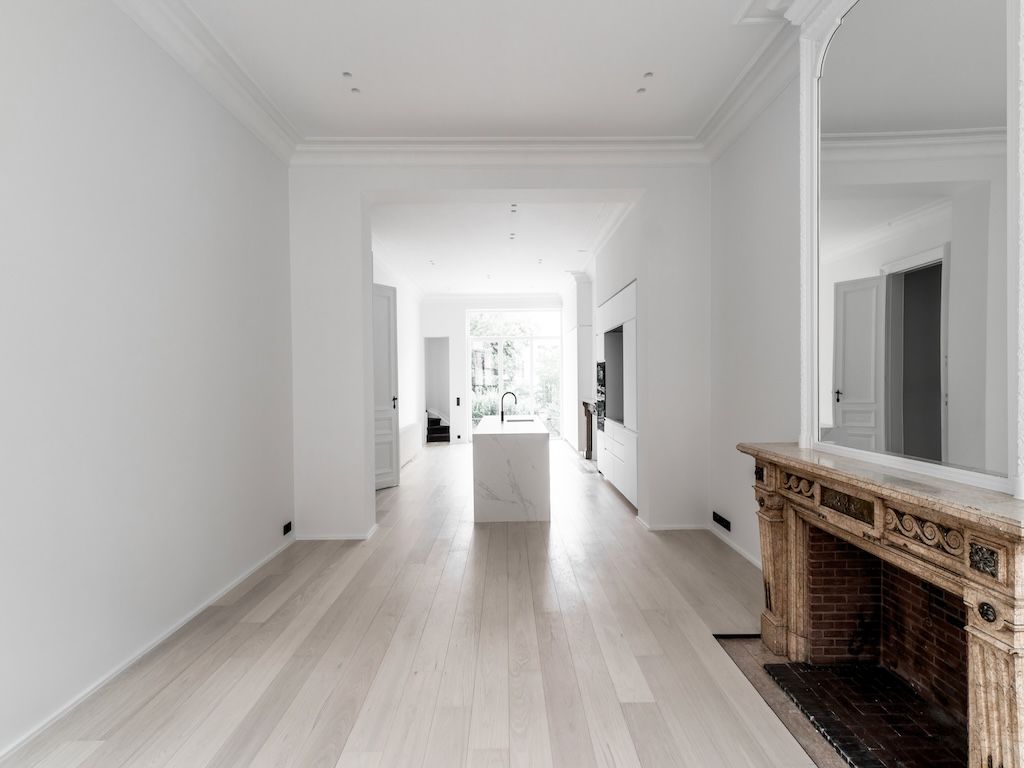 Intérieur moderne avec sol en bois, cuisine minimaliste et cheminée en briques rustique.