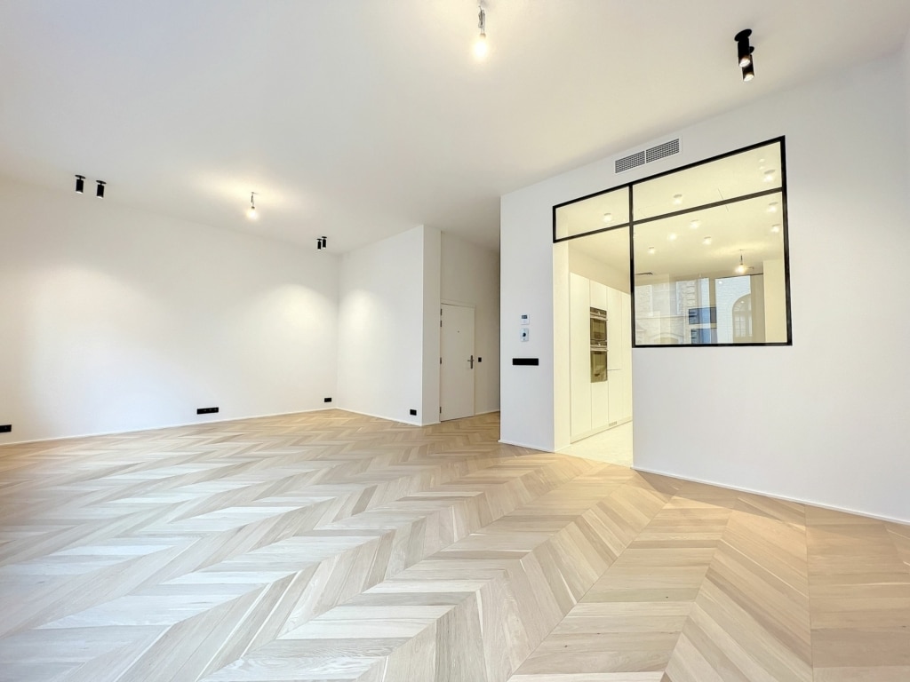 Intérieur moderne lumineux avec parquet en chevrons et mur en verre pour espace épuré et élégant.