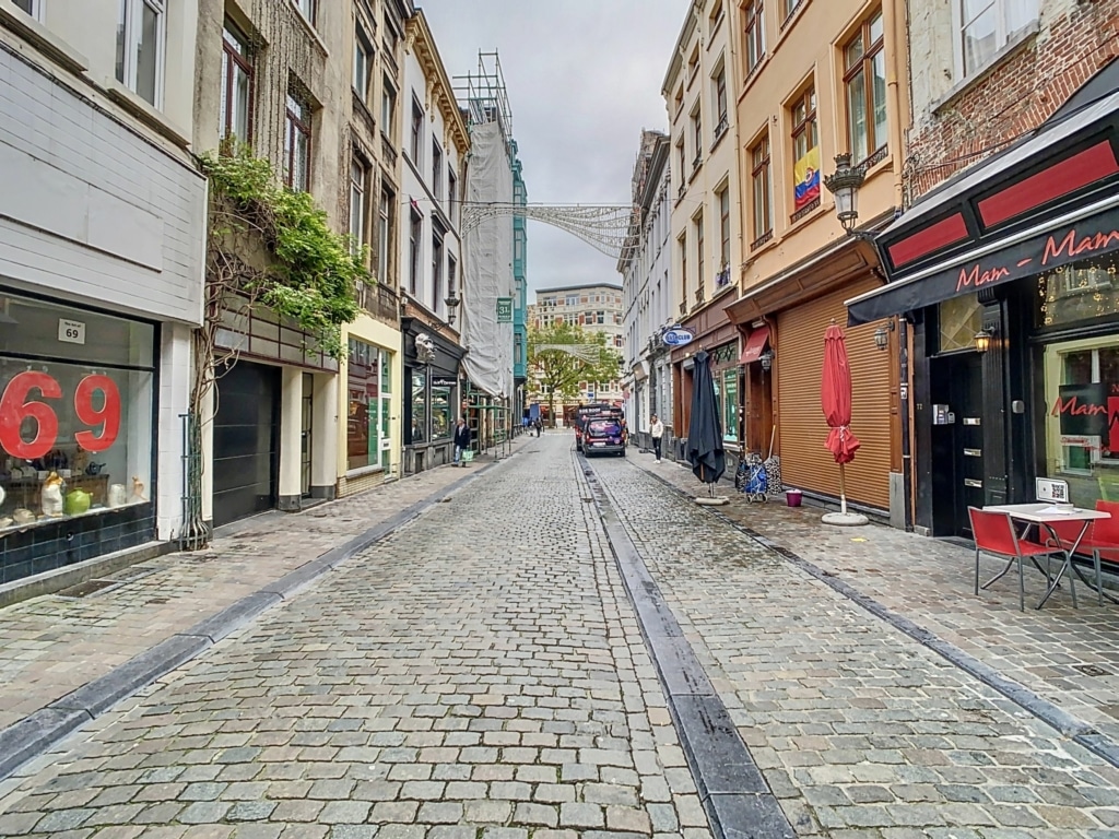 Rue pavée historique sous ciel gris, boutique, café charmant, ambiance paisible et rétro.