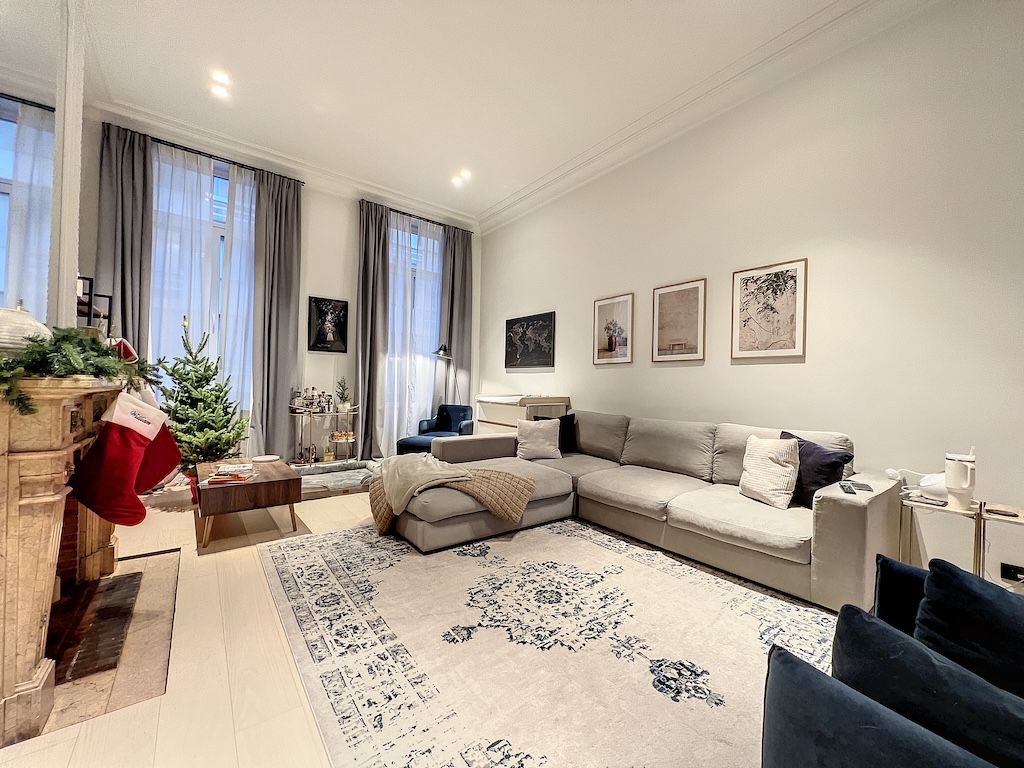 Salon moderne et cosy avec canapé gris, décor festif, cheminée, sapin de Noël et œuvres d’art.