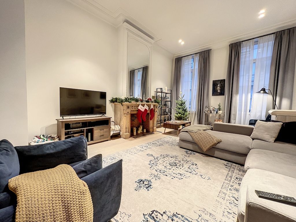 Salon moderne et chaleureux avec canapé gris, fauteuil bleu, luminaires douillets et décoration élégante.