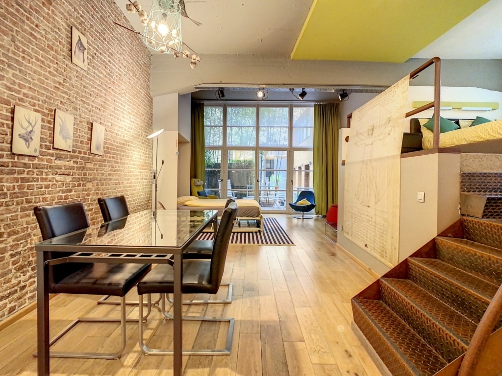 Salon moderne avec mur en brique, éclairage artistique, lumière naturelle et ambiance chaleureuse.