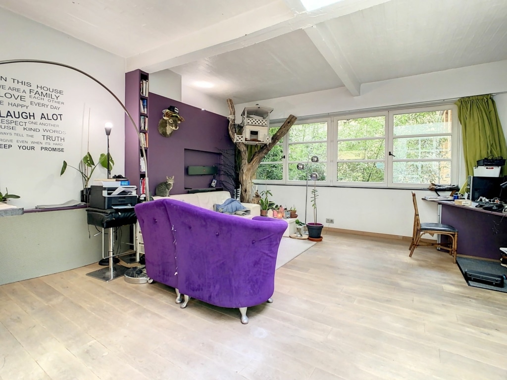 Salon lumineux avec canapé violet, espace de travail et décoration végétale inspirante.