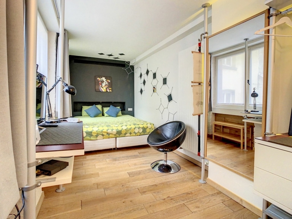Chambre moderne et cosy avec lit coloré, mobilier minimaliste, lumière naturelle, ambiance accueillante.