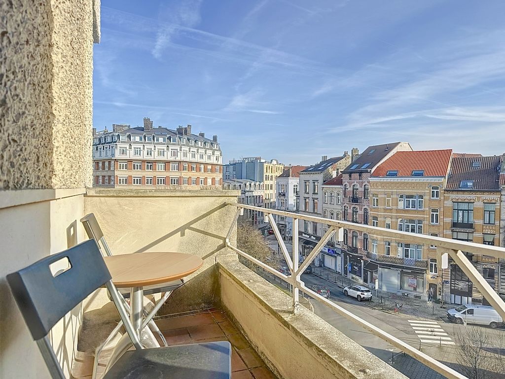Balcon charmant sur une rue urbaine animée avec bâtiments variés et ciel bleu.
