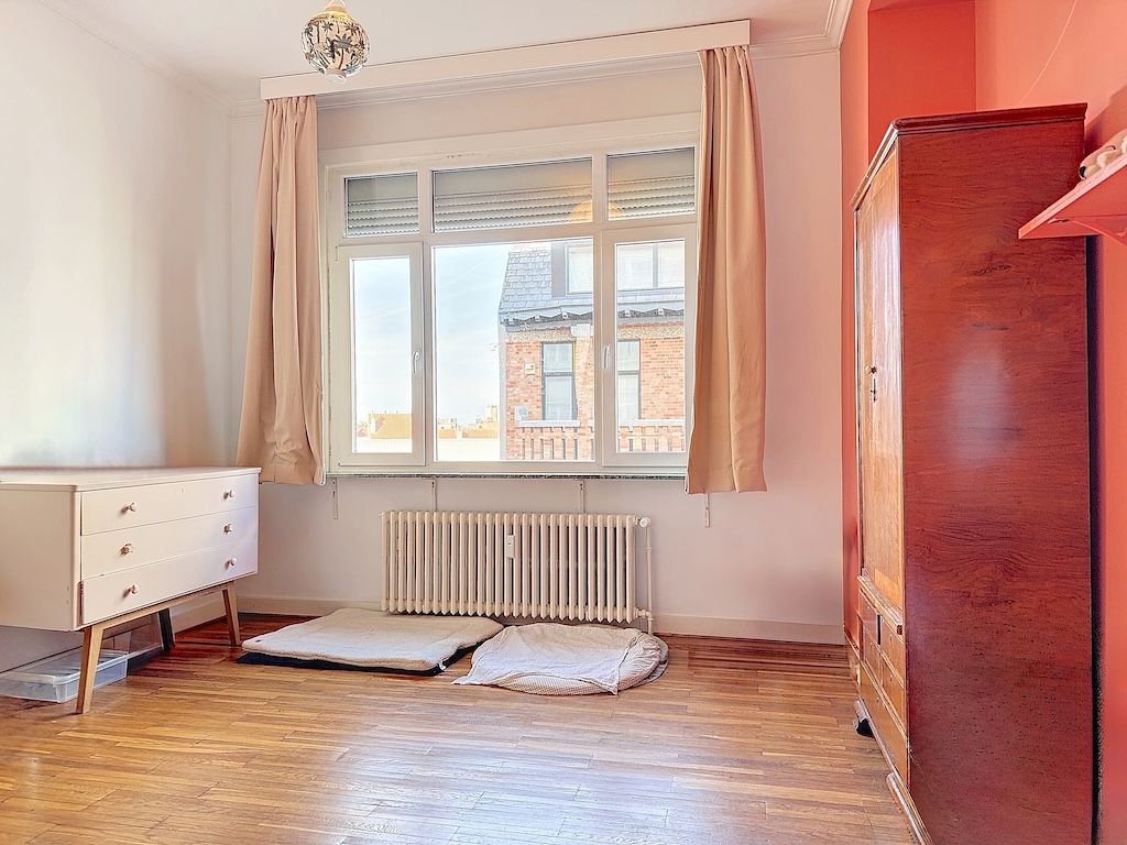 Salon lumineux avec meubles minimalistes, murs blancs et orange, baigné de lumière naturelle.