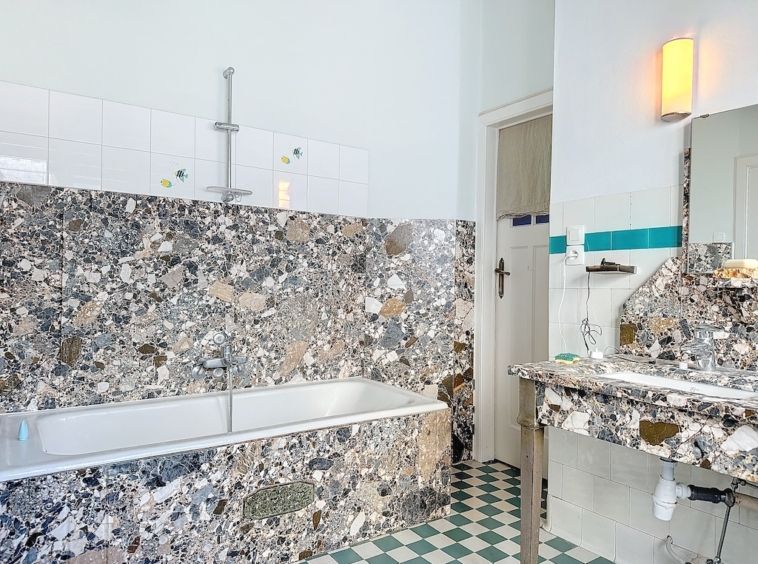 Salle de bain élégante avec pierre naturelle, carreaux vintage, baignoire intégrée et éclairage chaleureux