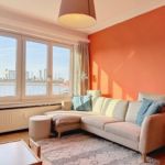 Salon moderne avec mur orange, canapé confortable, meubles en bois clair et décoration végétale.