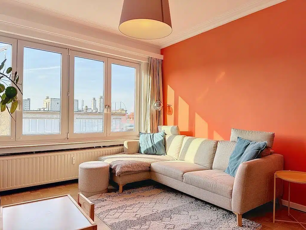 Moderne woonkamer met oranje muren en elegant comfort Woonkamer - Licht appartement met 2 slaapkamers + terras - Etterbeek