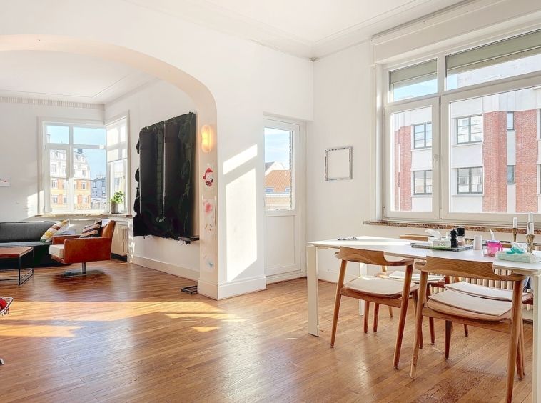 Salon lumineux et minimaliste avec archway, mobilier coloré et grande fenêtre panoramique.