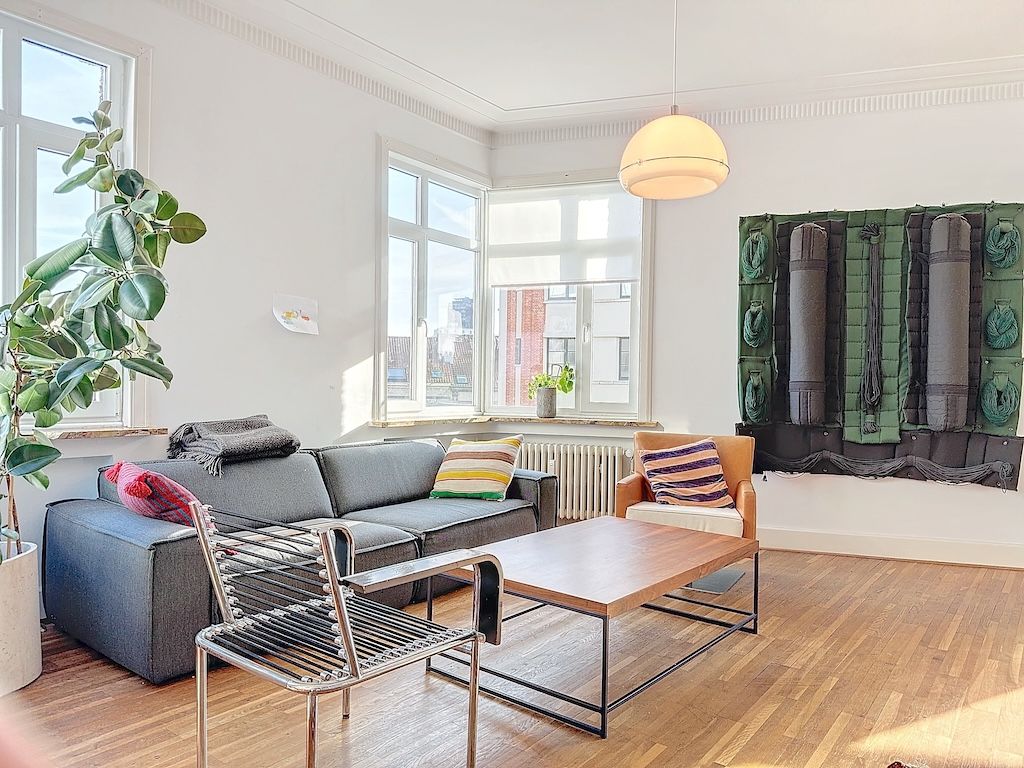 Salon moderne lumineux avec canapé gris, œuvres dart vert, plantes et mobilier contemporain.