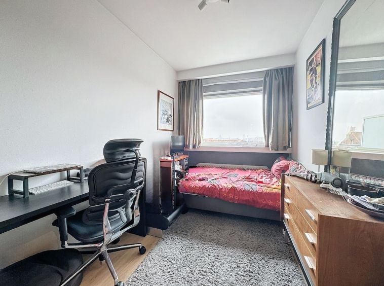 Chambre lumineuse et cosy avec bureau organisé, lit coloré, décor moderne et vue naturelle.