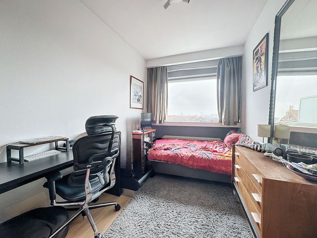 Chambre lumineuse et cosy avec bureau organisé, lit coloré, décor moderne et vue naturelle.