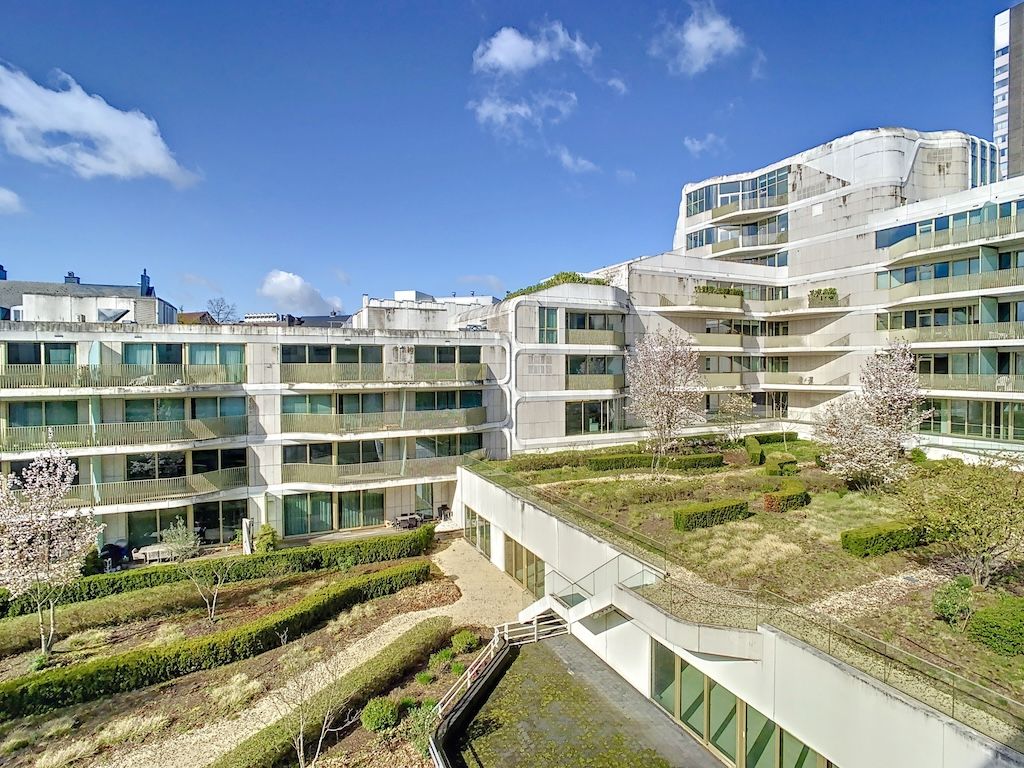 Complexe résidentiel moderne avec jardins, espaces verts, architecture contemporaine et éclairage naturel.
